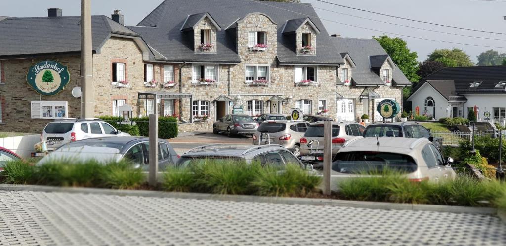 un estacionamiento con autos estacionados frente a un edificio en Charme - Hotel Lindenhof, en Bütgenbach