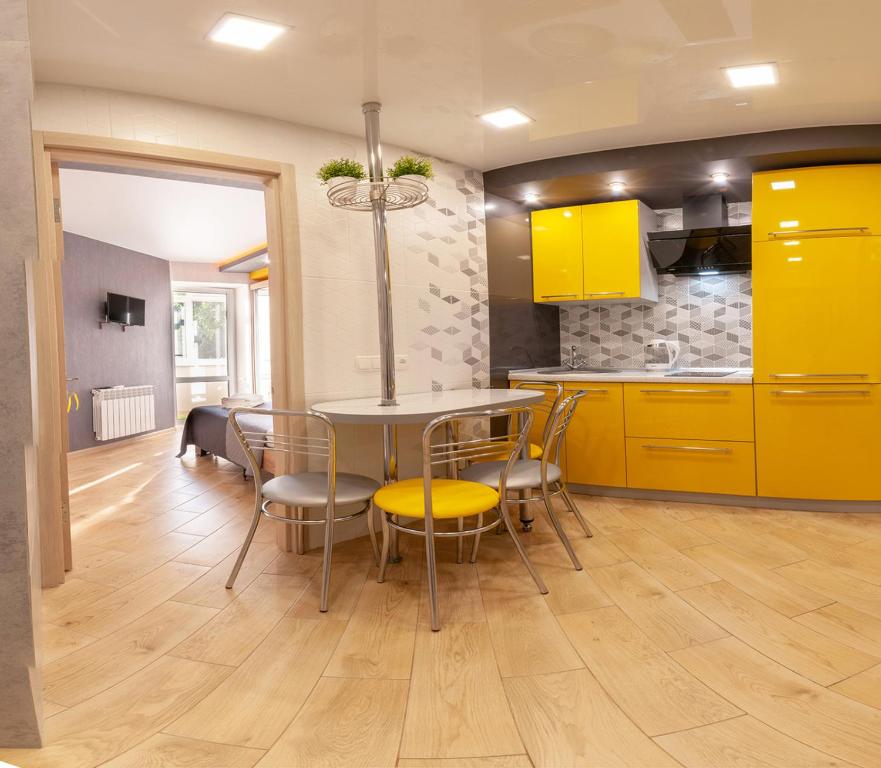 ポルタヴァにあるYellow Loft Luxury apartments with 2 bedroomsのキッチン(黄色のキャビネット、テーブル、椅子付)