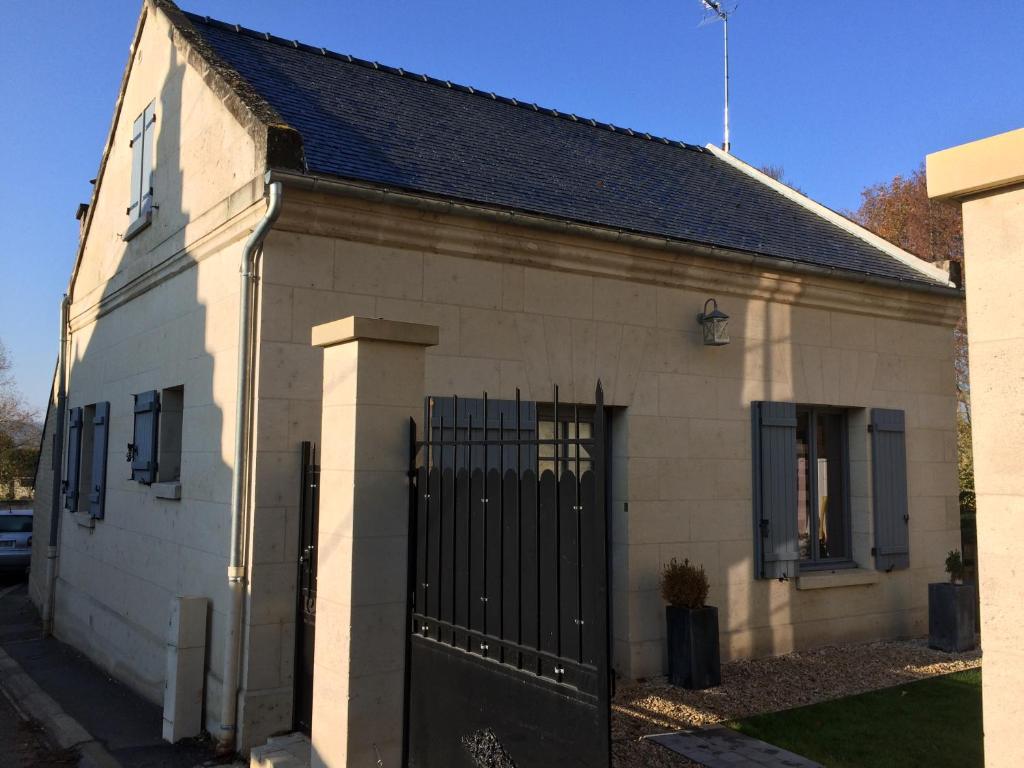 ein weißes Backsteinhaus mit einem schwarzen Tor in der Unterkunft Le Gîte du Château in Vic-sur-Aisne