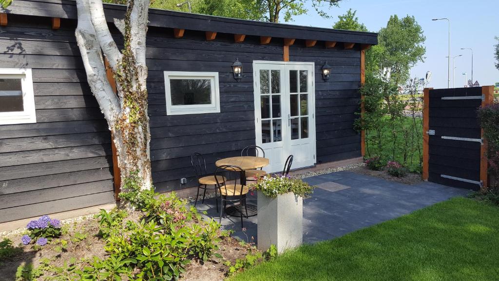 a black shed with a table and chairs in a yard at Chalet in Castricum
