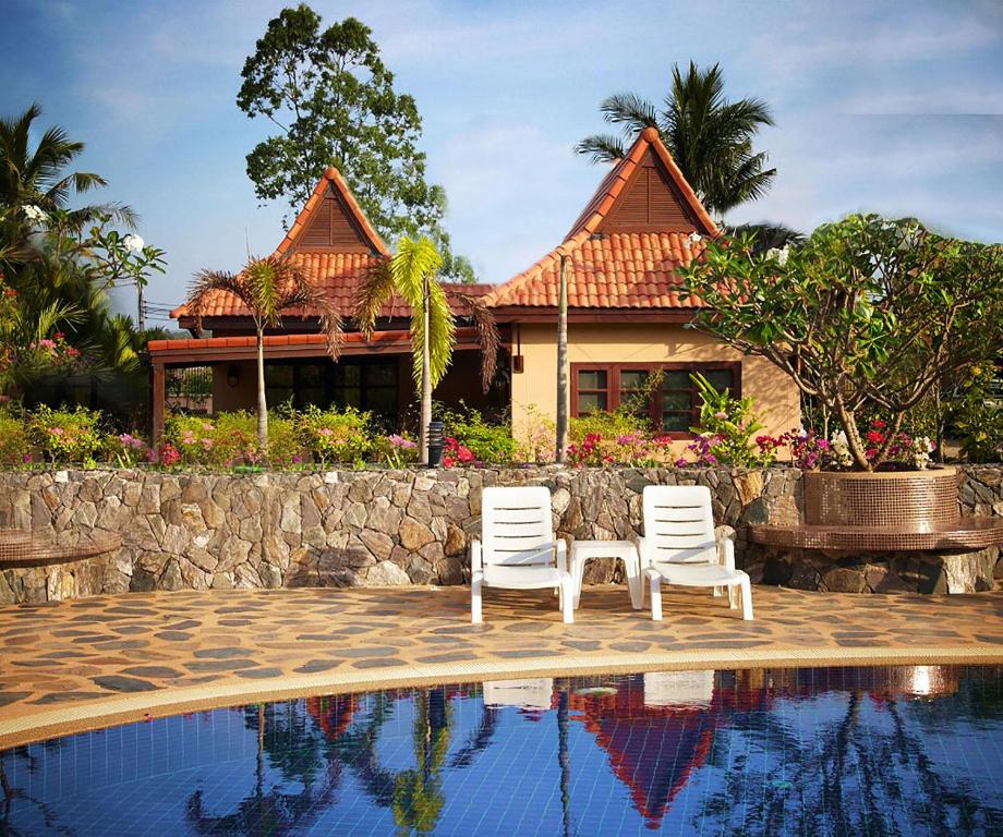 two white chairs next to a house with a pool at Family-friendly house, a few steps from the pool and close to the ocean. in Mae Pim