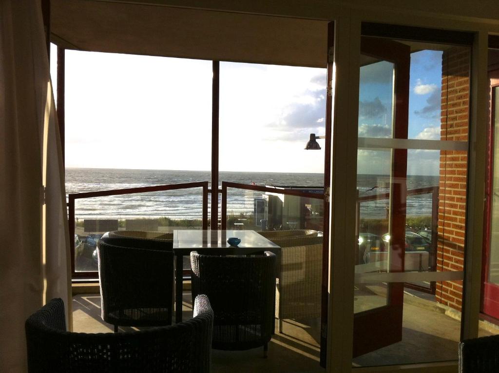 海邊的艾格蒙特的住宿－Strandhuis，阳台配有桌椅,享有海景。