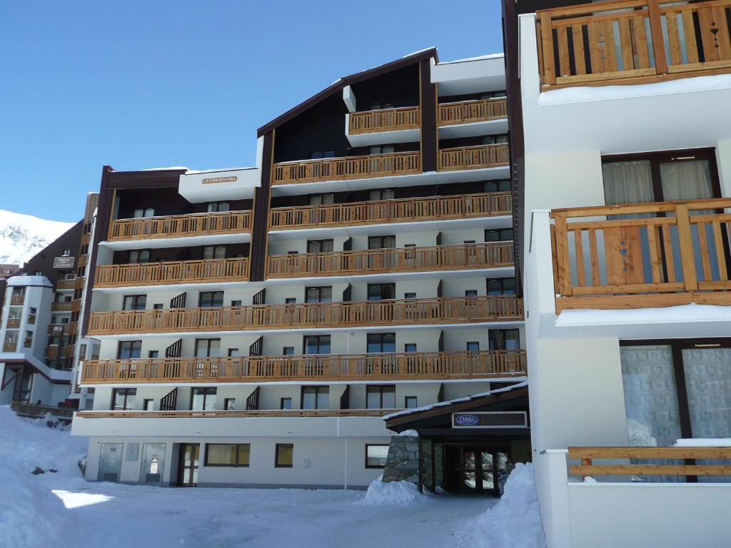 un grand bâtiment avec des balcons en bois dans la neige dans l'établissement LE CHRISTIANIA Les bergers, à L'Alpe-d'Huez