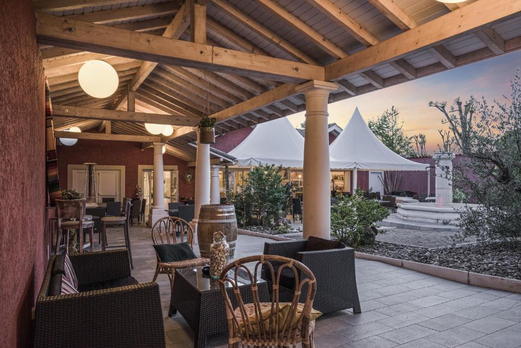 un patio con mesas y sillas bajo una pérgola de madera en The Originals Boutique, Hôtel Le Pillebois, Bourg-en-Bresse Nord en Malafretaz