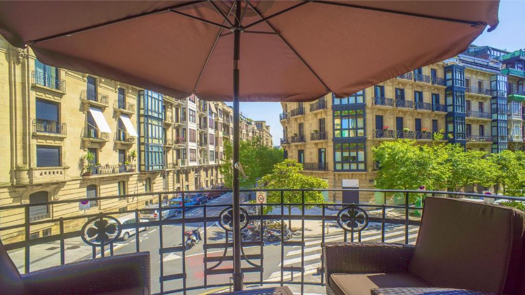 a balcony with an umbrella and a view of a street at Downtown Design Apartment in Donostia-San Sebastián