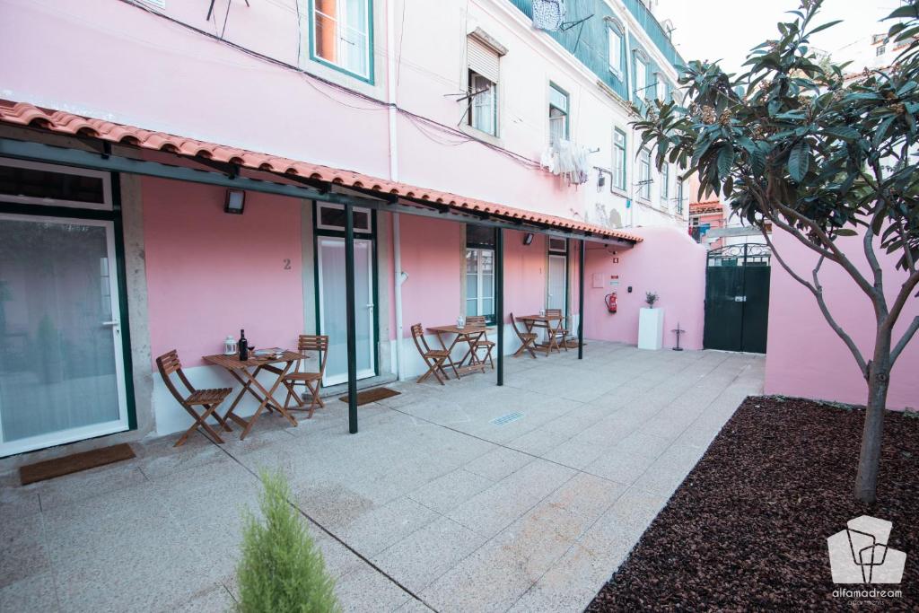 リスボンにあるAlfama Dream Apartmentsのピンクの建物内のパティオ(テーブル、椅子付)