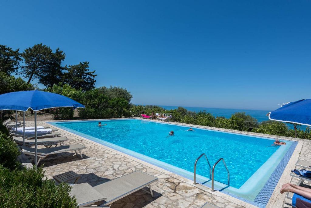 een zwembad met ligstoelen en een parasol bij Villa Palamara 1868 Apartments in Cefalù