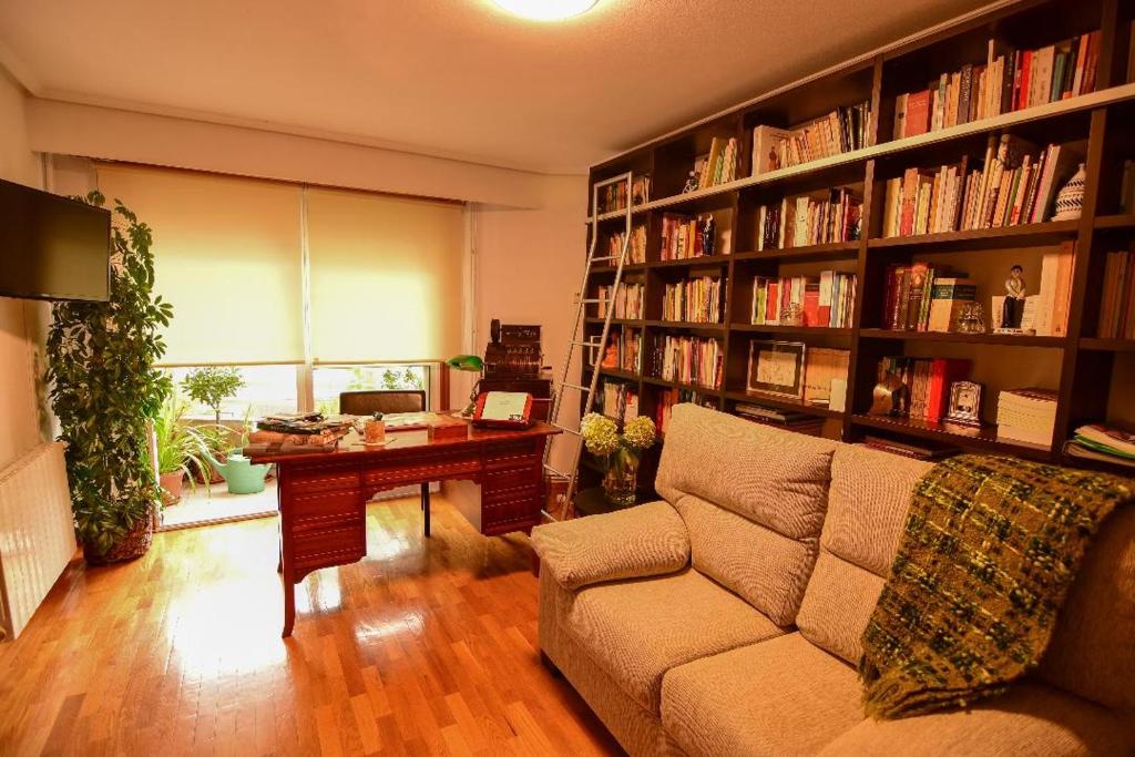 uma sala de estar com um sofá, uma secretária e prateleiras de livros em Vivienda Caseiro em Ourense