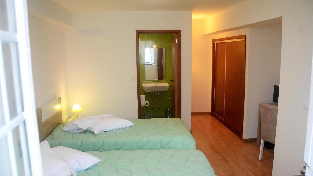 a room with two beds and a bathroom with a sink at BELO CAMPO - Ilha do Faial (Horta) in Castelo Branco