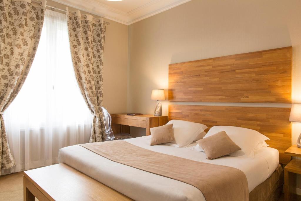 um quarto com uma cama com uma cabeceira em madeira e uma janela em Brit Hôtel Confort Cléria Lorient Centre em Lorient