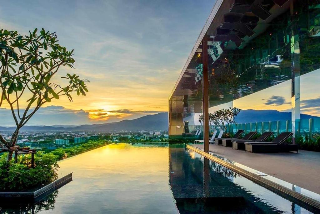 - un bâtiment avec une piscine offrant une vue sur la ville dans l'établissement The Astra Condo City Center Chiang Mai, à Chiang Mai
