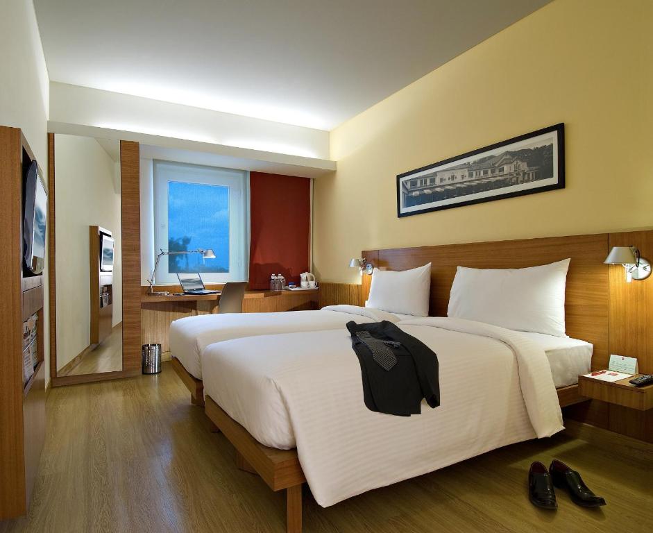 a bedroom with a large bed with a black shirt on it at ibis Pune Viman Nagar - An Accor Brand in Pune