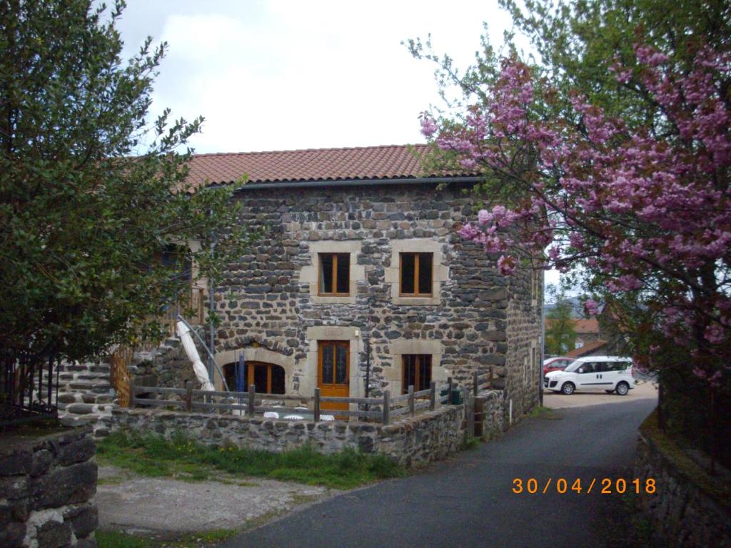 a stone building with a car parked in front of it at maison Mouilhade in Chaspuzac