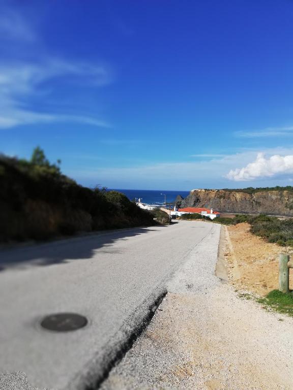 an empty road with the ocean in the background at Sol Mar in Odeceixe