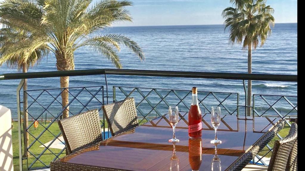 einen Tisch mit Weingläsern und Meerblick in der Unterkunft MI CAPRICHO C16 Beachfront Apartment in Mijas Costa