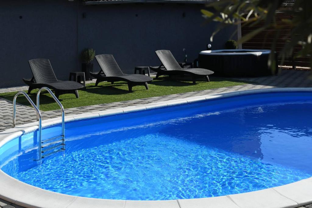 a blue swimming pool with chairs and a table at "Oasis of Peace Zagreb-Apartments" in Zagreb