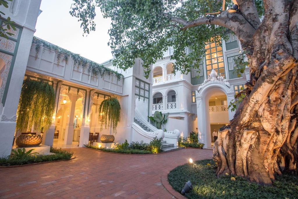 a large white mansion with a tree in the foreground at The Inside House in Chiang Mai