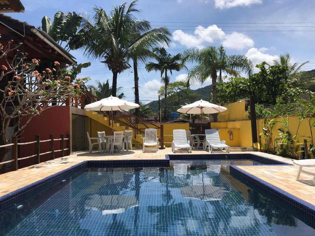 una piscina con sillas y sombrillas junto a una casa en Pousada Vila do Sol Juquehy, en Juquei