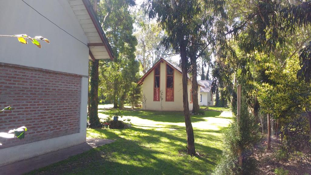 a small house in the middle of a yard with trees at Cabañas El Racó del Bosc in Mar del Plata