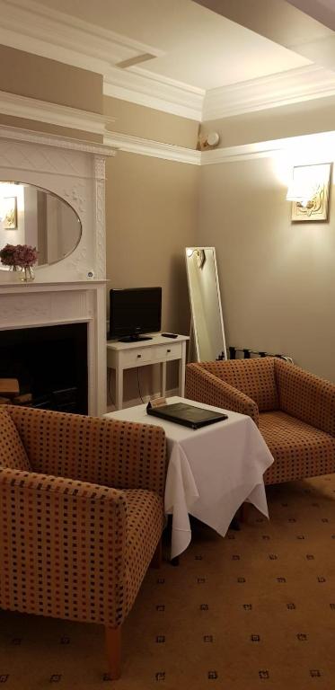 a living room with two chairs and a table at The Tudor Hotel in Harrow