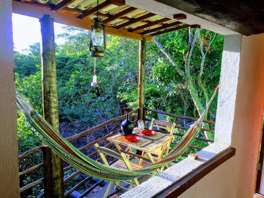 a room with a hammock and a table on a balcony at Conjunto Sol Roots in Pipa