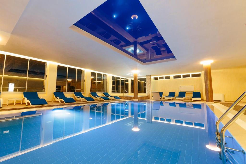 ein Pool in einem Hotel mit blauen Stühlen und einem Gebäude in der Unterkunft Spa&Hotel Studenac in Trebinje
