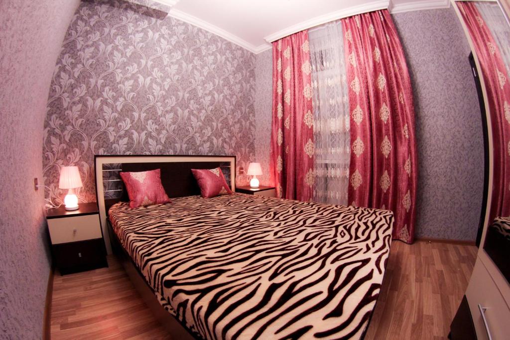 "METROPOL" APARTMENT HOTEL في باكو: غرفة نوم مع سرير ذو طابع حمار الوحشي مع مصباحين