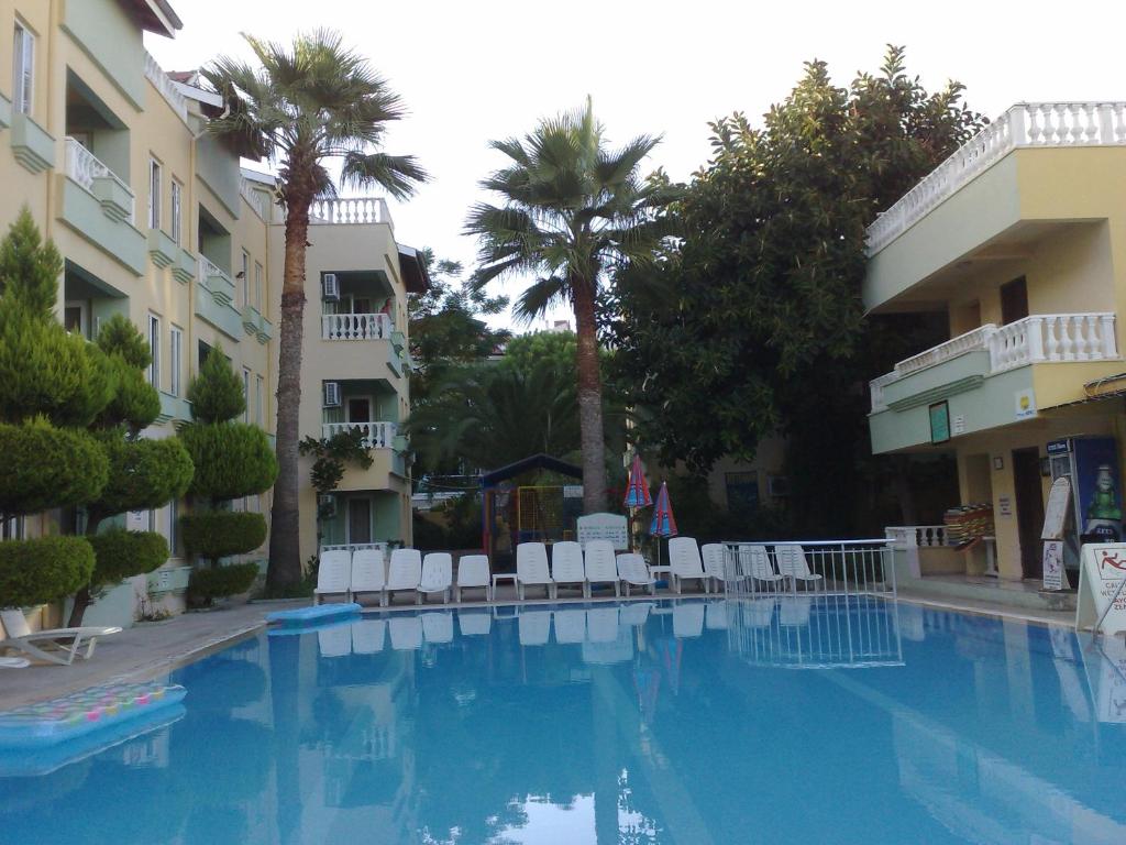 a swimming pool with chairs and palm trees next to a building at Club Sunset Apartments in Marmaris