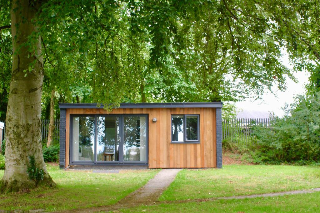 una casita en un campo con un árbol en Cozy Snowdonia Chalet en Caernarfon