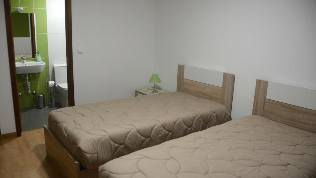 a bedroom with two beds and a sink and a mirror at BELO CAMPO - Ilha do Faial (Horta) in Castelo Branco