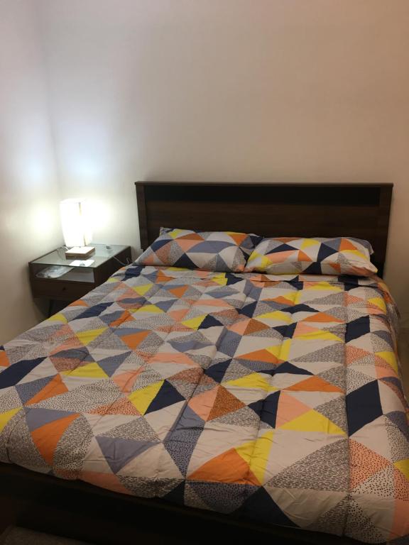 - un lit avec une couette colorée et une lampe sur une table dans l'établissement Trillium Residences Condominium, à Cebu