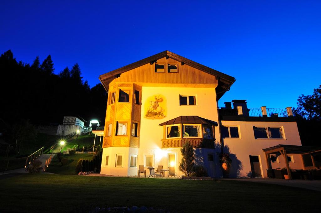 ein Haus mit seitlicher Beleuchtung in der Nacht in der Unterkunft Hotel-Garni Drachenburg in Mittenwald