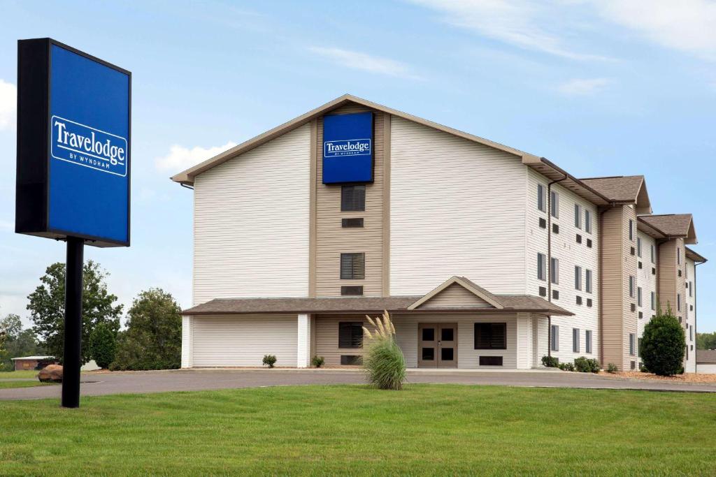 a building with a blue sign in front of it at Travelodge by Wyndham Livonia in Livonia