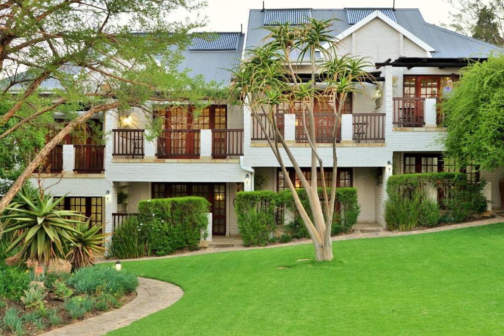 una casa con un césped verde delante de ella en Rivonia Premier Lodge en Johannesburgo