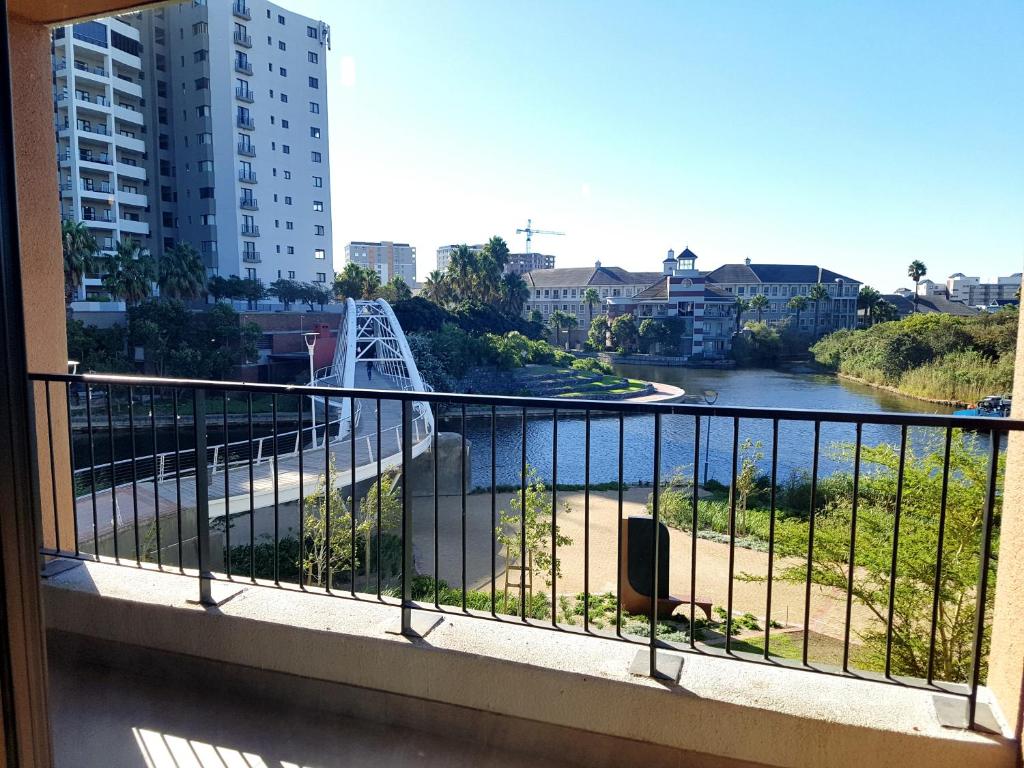 einen Balkon mit Blick auf den Fluss und die Gebäude in der Unterkunft WATERS EDGE 103 in Kapstadt