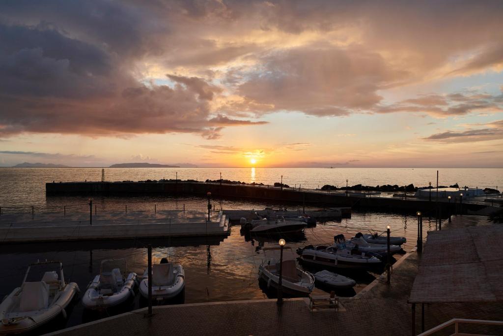 a group of boats docked at a dock with the sunset at Hotel Tirreno in Trapani