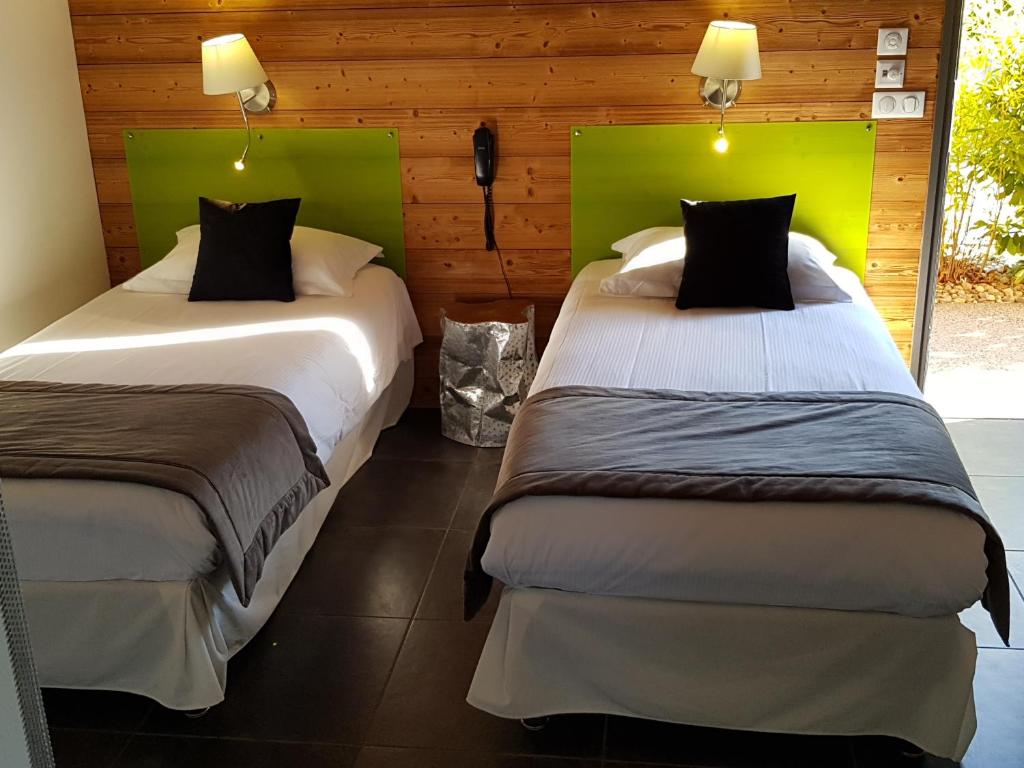 two beds in a room with green headboards at Bio-Motel in Saint-Vulbas