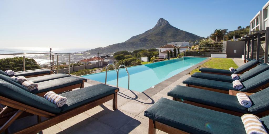 una fila di sedie a sdraio accanto alla piscina di The Crystal Apartments a Città del Capo
