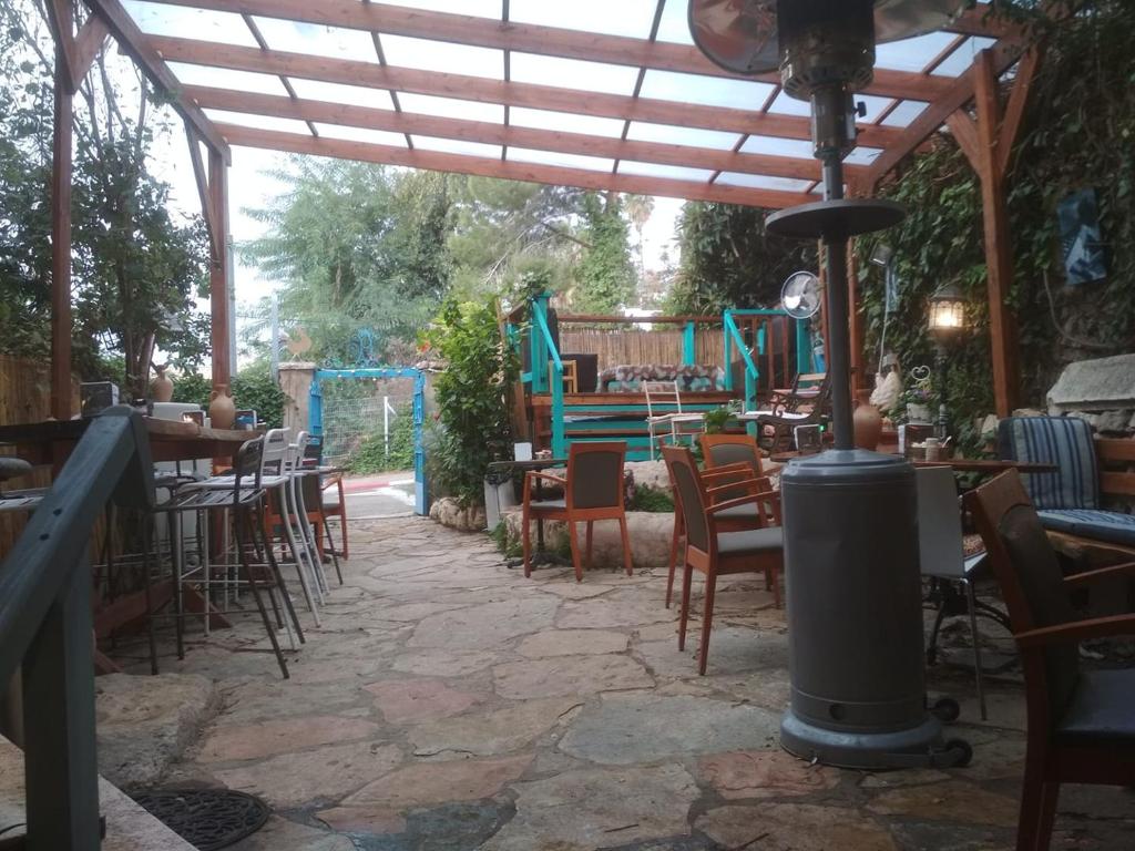 a patio with tables and chairs under a wooden pergola at Sweet ‘En Kerem View in Jerusalem