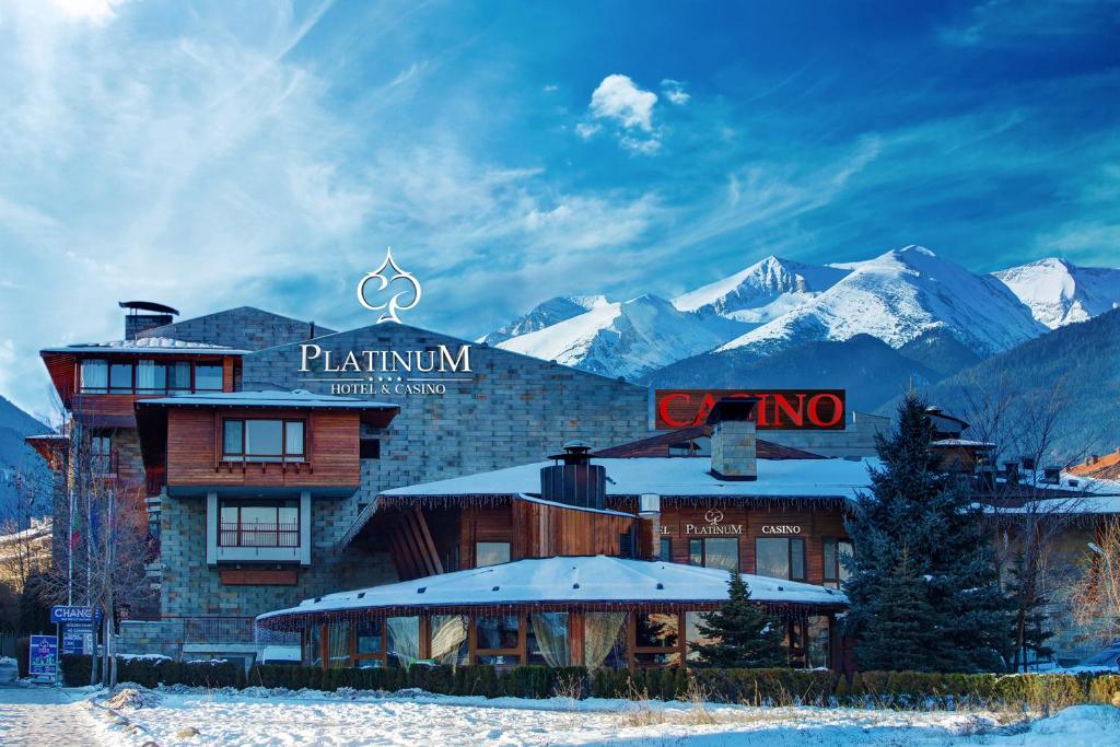 a hotel with snow covered mountains in the background at Platinum Hotel and Casino Bansko in Bansko