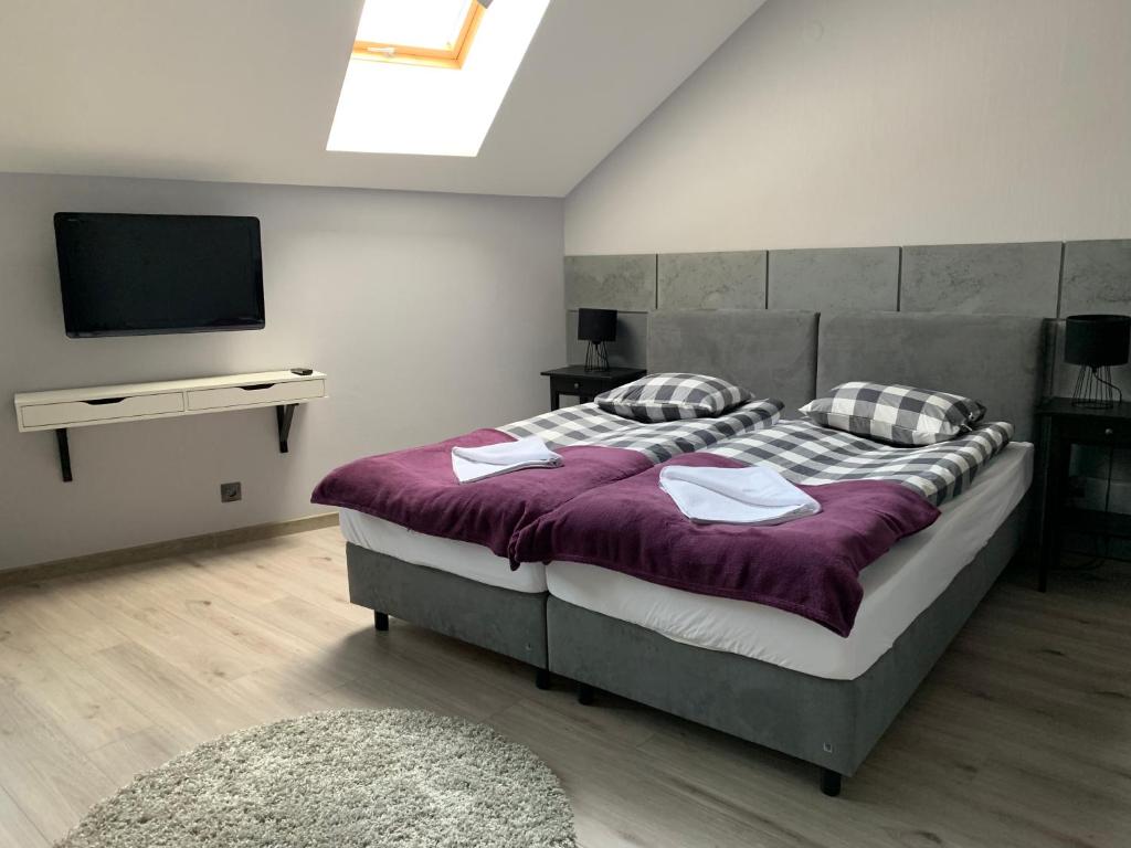 a bedroom with a large bed and a flat screen tv at Arkada Wadowice in Wadowice