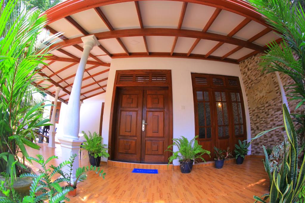 an entry to a house with wooden doors and plants at Abinu"s Place in Dickwella