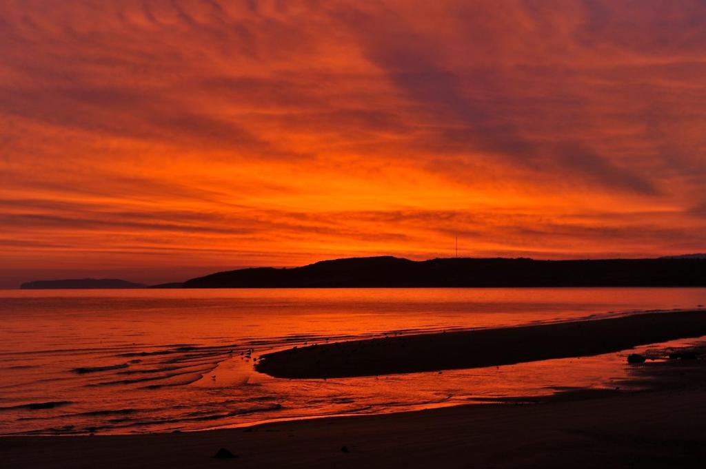 a sunset on a beach with the ocean at Sea View Guest House in Benllech