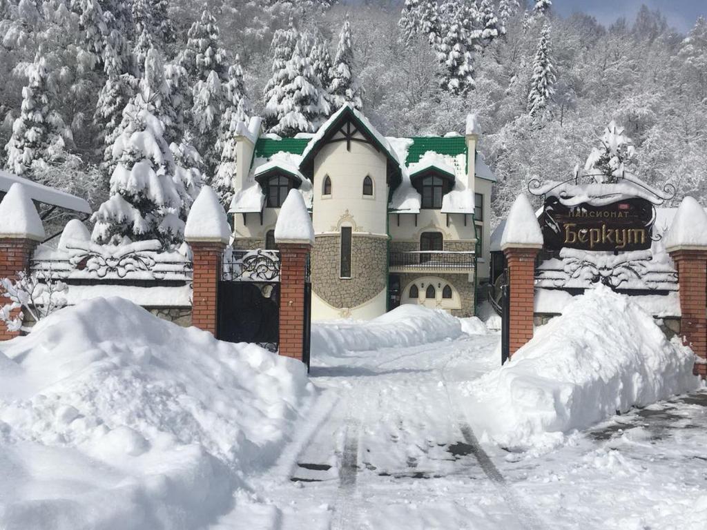 a castle covered in snow in front of a building at Hotel Berkut in Belokurikha