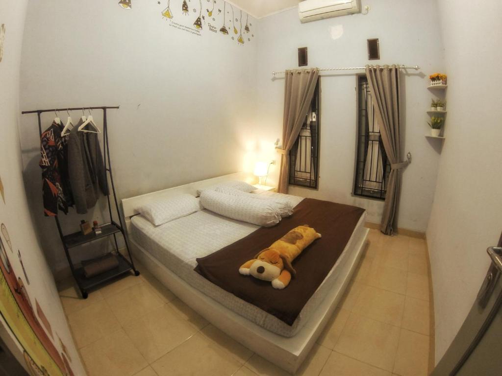 a bedroom with a bed with a teddy bear on it at Rumah Ayin Homestay Near Airport in Palembang