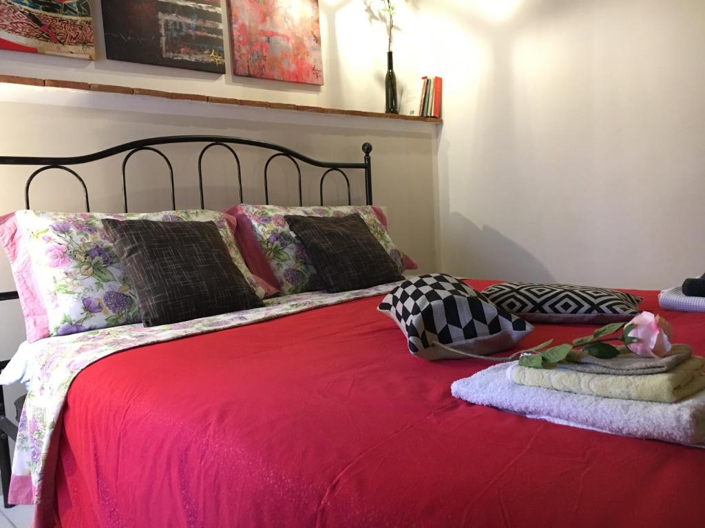 1 cama con manta roja y almohadas en New Maria's House Livorno. Il Cisternone en Livorno
