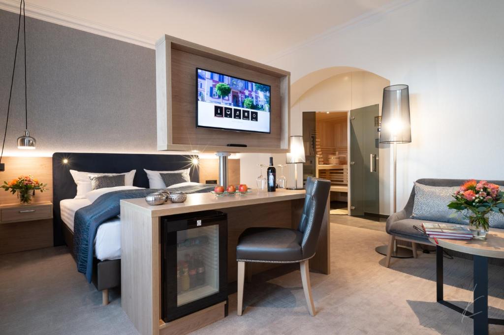 ベンドルフにあるRomantik Hotel Villa Saynのベッド1台、壁掛けテレビが備わるホテルルームです。