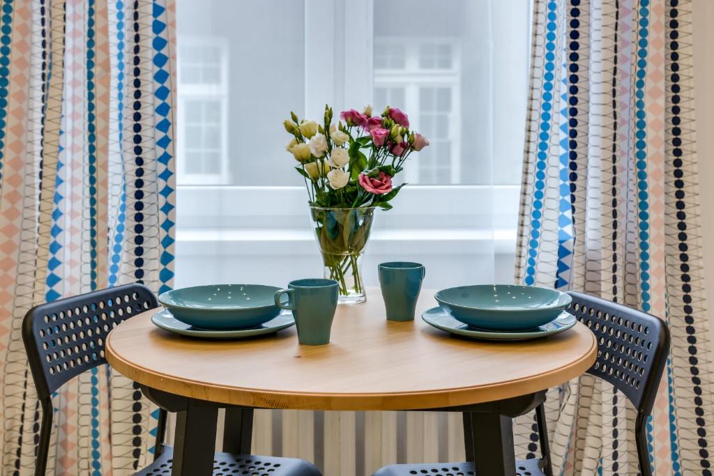 una mesa con dos platos y un jarrón de flores en KATO Apartamenty Moniuszki, en Katowice