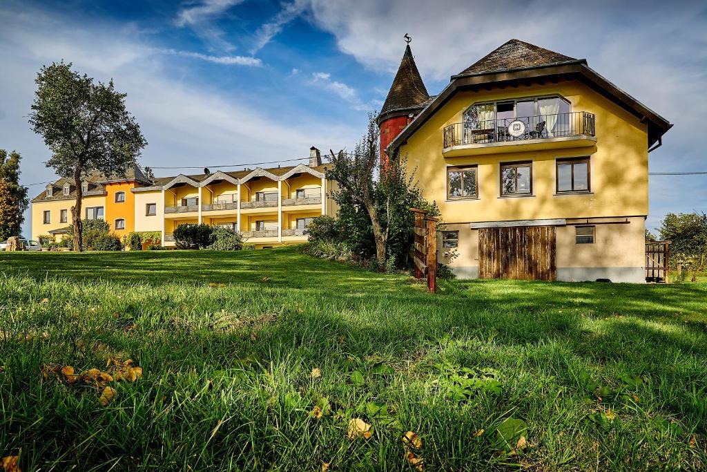 ein großes gelbes Gebäude auf einem Grasfeld in der Unterkunft Hofgut Held in Prüm