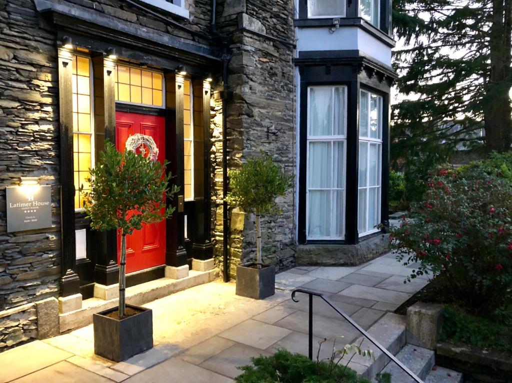 a red door on a stone building with two potted plants at Latimer House in Bowness-on-Windermere